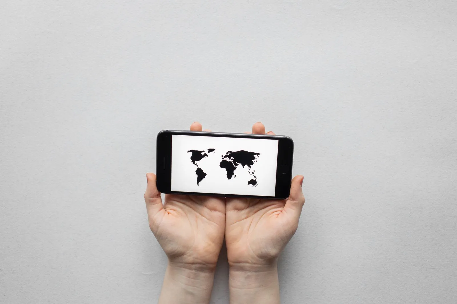 Palm holding a phone showing a world map, illustrating global sourcing reach